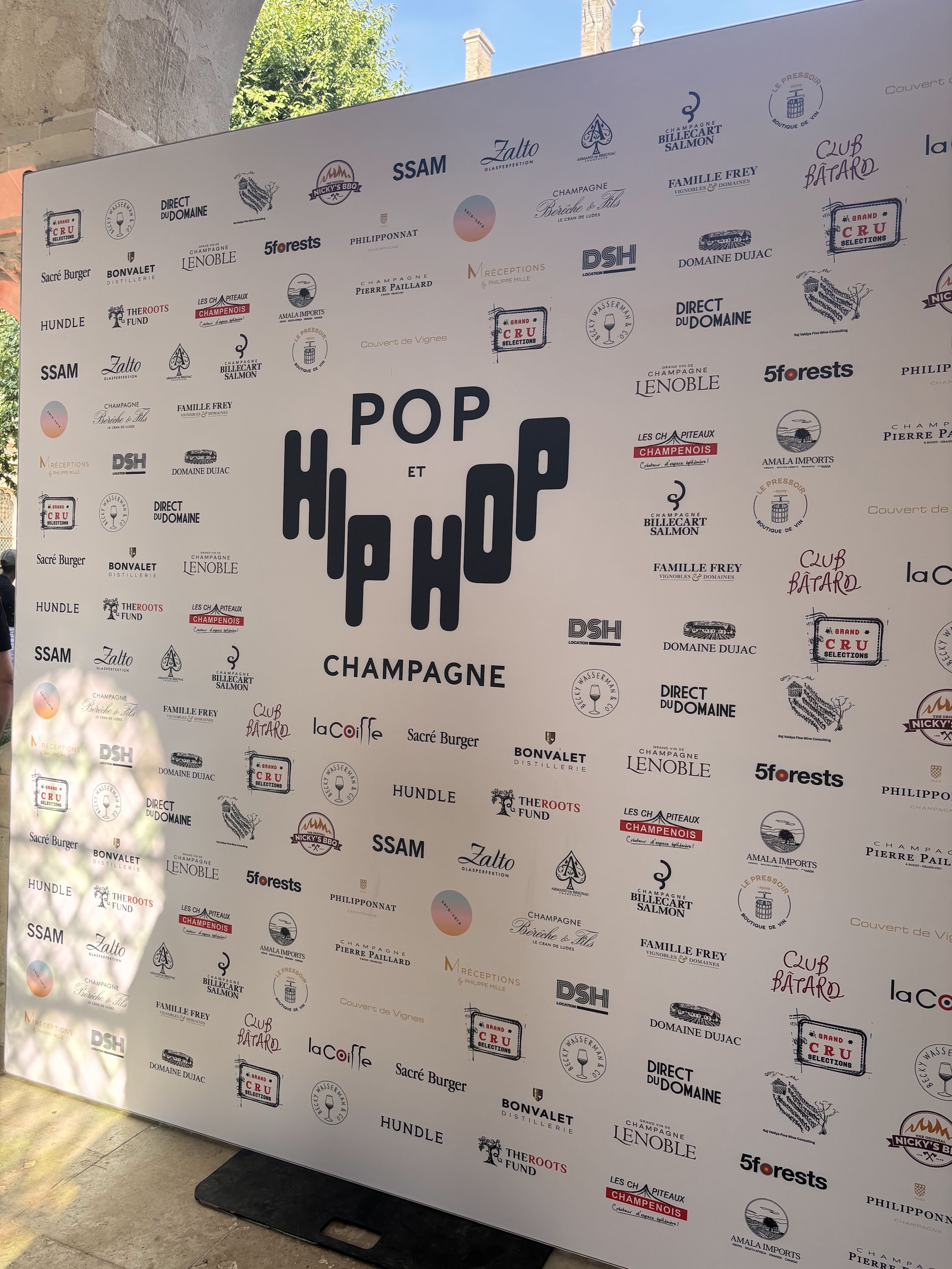 Event backdrop featuring the text 'POP et HIP HOP' with multiple logos of sponsors and partners related to champagne and gastronomy.