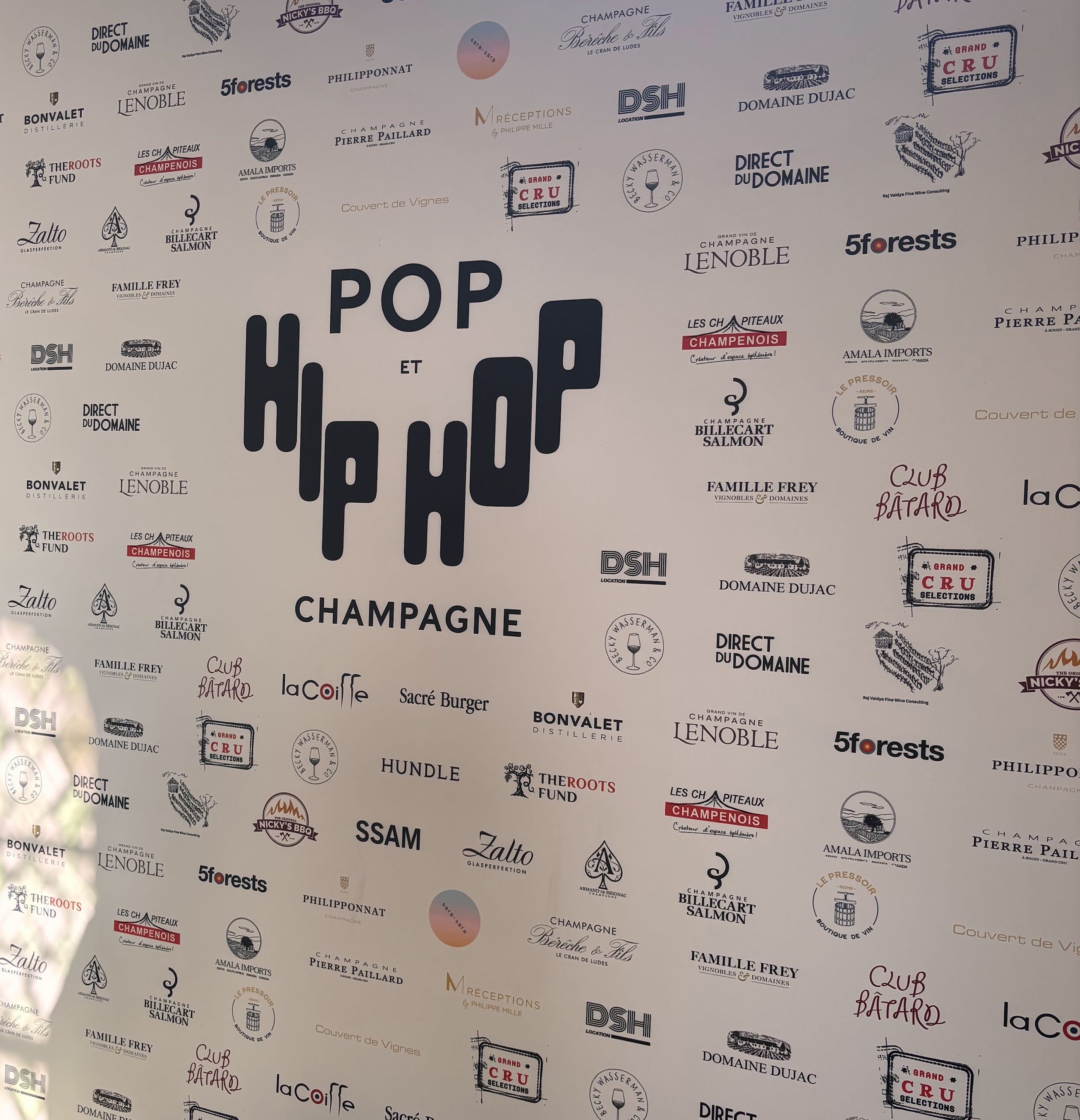Event backdrop featuring the text 'POP et HIP HOP' with multiple logos of sponsors and partners related to champagne and gastronomy.